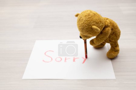 Photo for Teddy bear writing 'sorry' on paper - Royalty Free Image