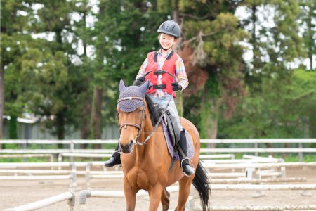 Girl wearing a helmet enjoying horseback riding