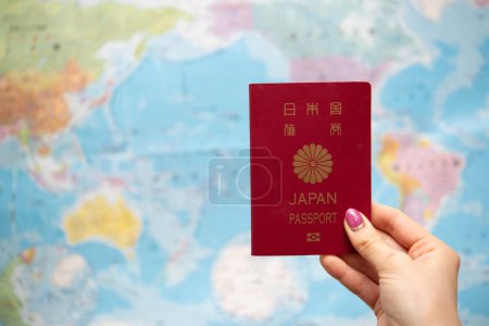 Foto de Mano de mujer sosteniendo pasaporte japonés y mapa del mundo - Imagen libre de derechos