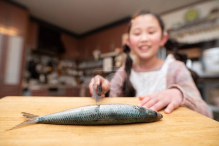 Photo for Girl cooking sardine with a kitchen knife - Royalty Free Image