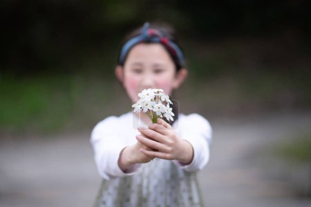 Photo for Girl holding out white flowers - Royalty Free Image