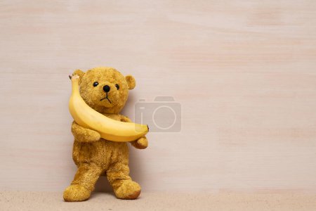 Photo for Teddy bear holding a banana - Royalty Free Image
