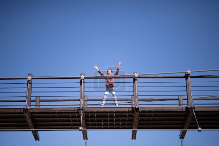 Photo for Child waving from suspension bridge - Royalty Free Image