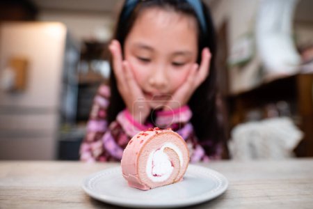 Téléchargez les photos : Fille manger un gâteau rouleau rose - en image libre de droit