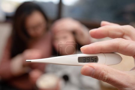 Téléchargez les photos : Un enfant malade, une mère inquiète, et une main avec un thermomètre - en image libre de droit