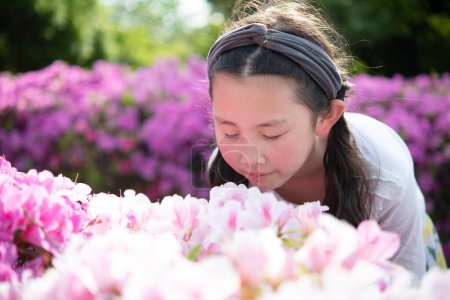 Téléchargez les photos : Fille sentant le parfum des fleurs et souriant - en image libre de droit