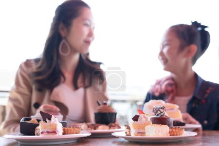 Foto de Madre e hija comiendo un montón de dulces - Imagen libre de derechos