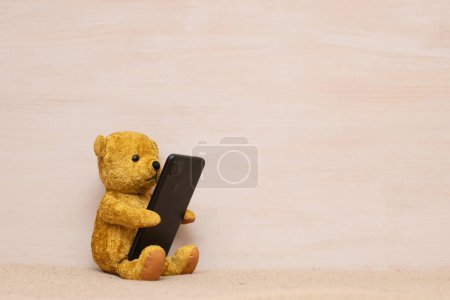 Photo for Teddy bear looking at smartphone - Royalty Free Image