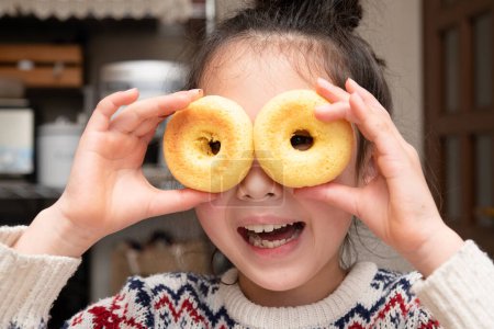 Photo for Girl peeking through a holes in a donuts - Royalty Free Image