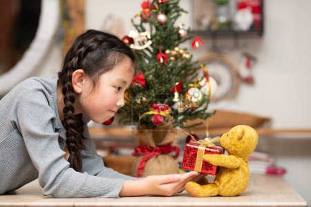 Photo for Girl receiving a Christmas gift from a teddy bear - Royalty Free Image