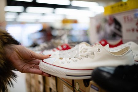 Téléchargez les photos : Mains féminines choisissant des chaussures dans le magasin - en image libre de droit