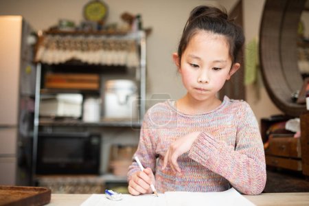 Téléchargez les photos : Fille faire des devoirs à la maison - en image libre de droit
