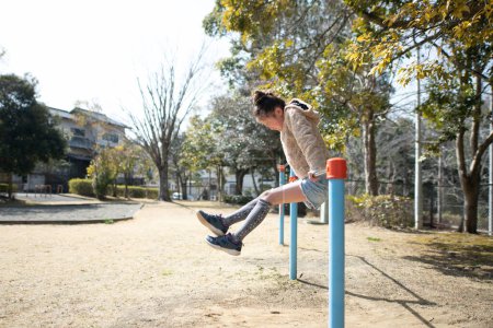 Téléchargez les photos : Fille jouer sur la barre horizontale dans le parc - en image libre de droit