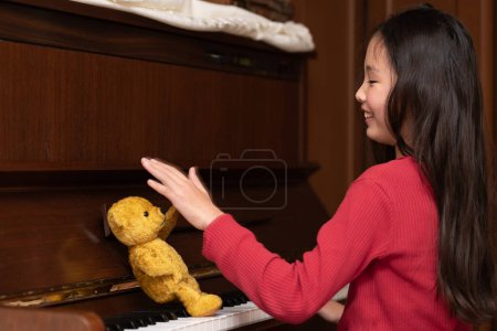 Foto de Osito de peluche enseñando piano a chica - Imagen libre de derechos