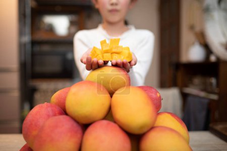 Téléchargez les photos : Enfant tenant une mangue coupée - en image libre de droit