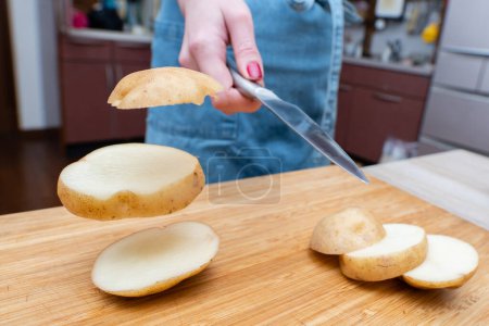 Téléchargez les photos : Une main de femme tranchant des pommes de terre rapidement - en image libre de droit