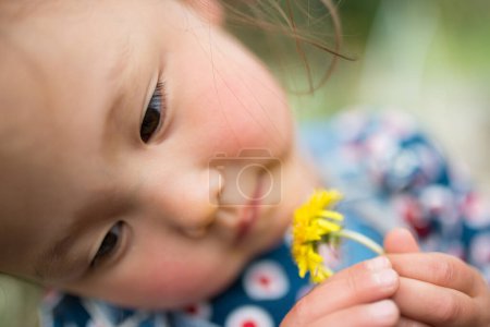 Photo for Girl sniffing the scent of a small flower - Royalty Free Image
