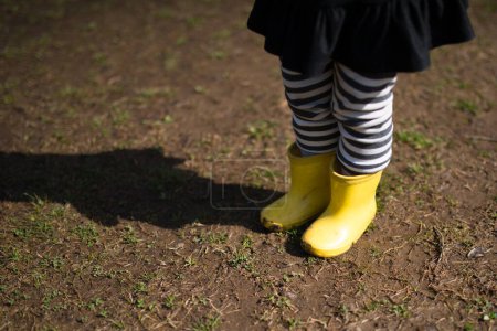 Foto de Chica en botas de goma amarillas en un paseo en un día soleado - Imagen libre de derechos