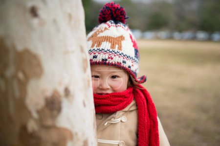 Téléchargez les photos : Belle petite fille asiatique jouer dans le parc d'hiver, souriant et profiter de jour d'hiver - en image libre de droit