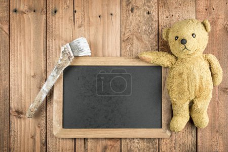 Téléchargez les photos : Pinceau, tableau noir et ours en peluche sur fond en bois - en image libre de droit
