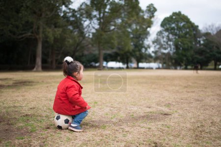 Téléchargez les photos : Fille assise sur le ballon de football - en image libre de droit