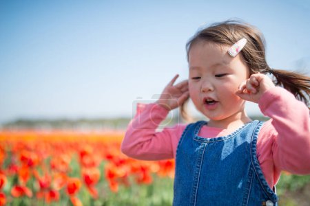 Téléchargez les photos : Mignonne petite fille asiatique avec des fleurs de tulipe - en image libre de droit
