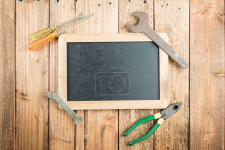 Photo for Old tools and blackboard on wooden background - Royalty Free Image