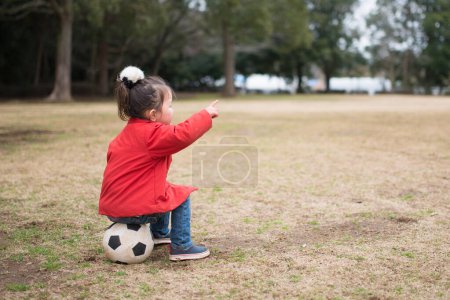 Foto de Chica sentada en la pelota de fútbol - Imagen libre de derechos