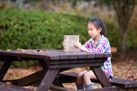 Téléchargez les photos : Fille lisant un livre sur un banc de parc - en image libre de droit