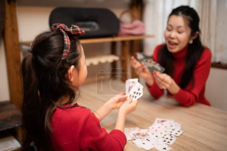 Téléchargez les photos : Mère et fille jouer à des jeux de cartes à la maison - en image libre de droit