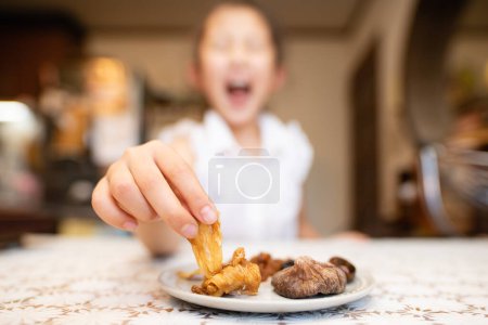 Téléchargez les photos : Enfant mangeant des fruits secs dans la cuisine - en image libre de droit