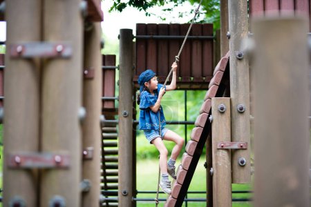 Téléchargez les photos : Fille escalade une corde dans le parc - en image libre de droit