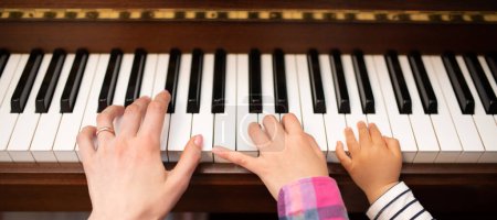 Téléchargez les photos : Mains du parent et de l'enfant jouant du piano - en image libre de droit