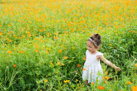 Téléchargez les photos : Fille jouant dans le jardin de fleurs - en image libre de droit
