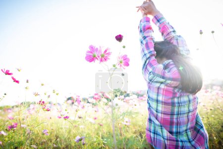 Téléchargez les photos : Fille levant les deux mains dans un champ de fleurs - en image libre de droit