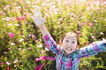Foto de Chica levantando ambas manos en un campo de flores - Imagen libre de derechos
