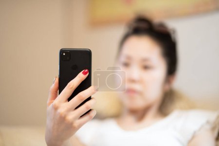 Foto de Mujer mirando un teléfono inteligente en la habitación - Imagen libre de derechos