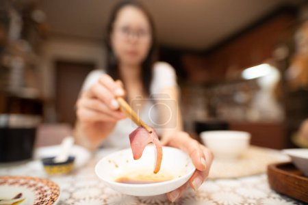 Photo for A woman holding sashimi with chopsticks and applying soy sauce - Royalty Free Image