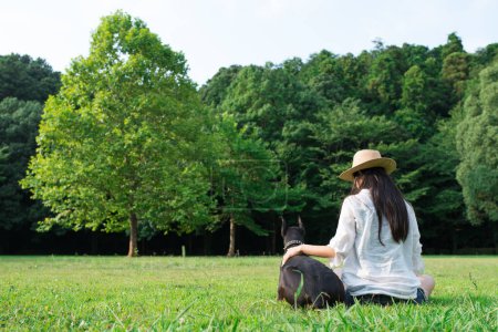 Photo for Woman relaxing on the lawn with Doberman - Royalty Free Image