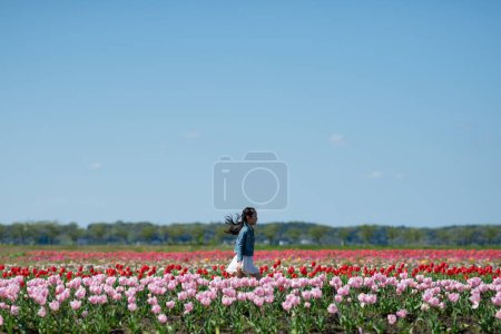 Téléchargez les photos : Jeune fille debout sur le terrain avec des tulipes - en image libre de droit