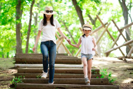 Photo for Mother and daughter walking hand in hand in forest stairs - Royalty Free Image