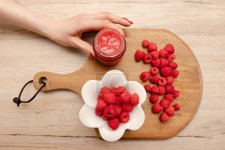 Photo for Raspberries and female hand on the table - Royalty Free Image