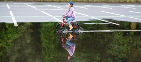 Foto de Chica montando una bicicleta en un charco - Imagen libre de derechos