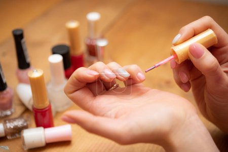 Téléchargez les photos : Femme appliquant vernis à ongles rose - en image libre de droit