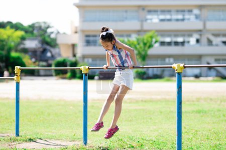 Photo for Girl playing horizontal bar in the schoolyard - Royalty Free Image