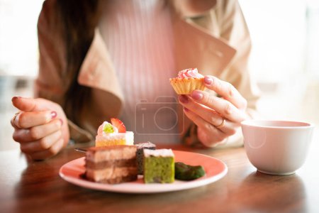 Téléchargez les photos : Femme mangeant des bonbons dans un café - en image libre de droit