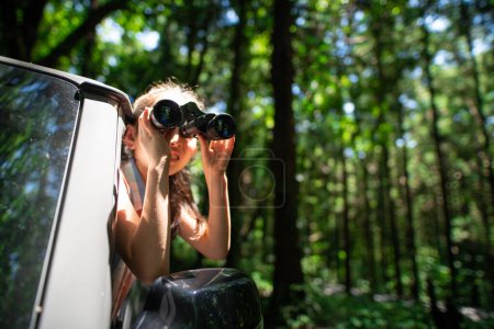 Photo for A child leaning out of a car window and using binoculars - Royalty Free Image
