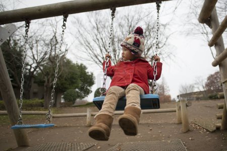 Foto de Chica jugando en swing en parque infantil - Imagen libre de derechos