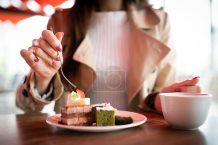 Téléchargez les photos : Femme mangeant des bonbons dans un café - en image libre de droit