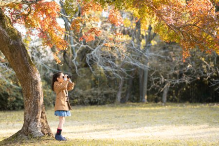 Téléchargez les photos : Fille à l'aide de jumelles dans la forêt d'automne - en image libre de droit